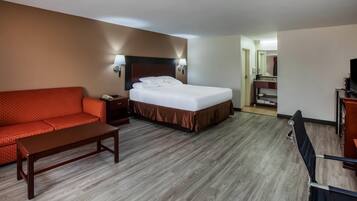 A hotel room with a bed, a sofa, a desk, and a TV.