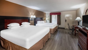 A hotel room with three beds, a desk, a television, and a chair. - Days Inn & Suites by Wyndham Tyler (Tyler)