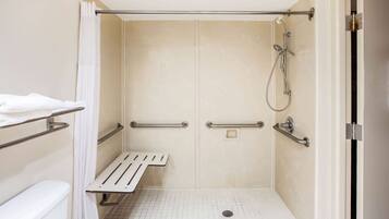 A wheelchair-accessible shower area with grab bars, a bench, and a toilet.