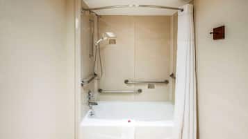 Ducha a pie con bañera, barras de apoyo y cabezal de ducha.