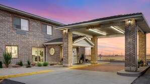 A brick building with a covered entrance, a sign indicating a 11'-0" clearance, and a clear sky at dusk. - Quality Inn & Suites Fillmore I-15 (Fillmore)