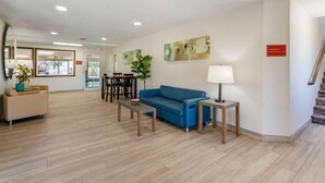 A modern lobby with a blue sofa, a coffee table, a lamp, and a sign indicating the breakfast and room locations. - Quality Inn & Suites Fillmore I-15 (Fillmore)