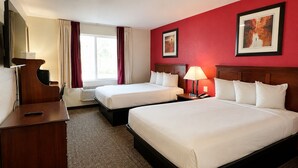 A hotel room with two beds, a desk, a chair, a TV, and a window with curtains.