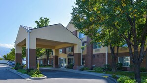 A hotel entrance with a covered walkway, a parking lot, and a landscaped area with trees. - Fairfield Inn by Marriott Salt Lake City Layton (Layton)
