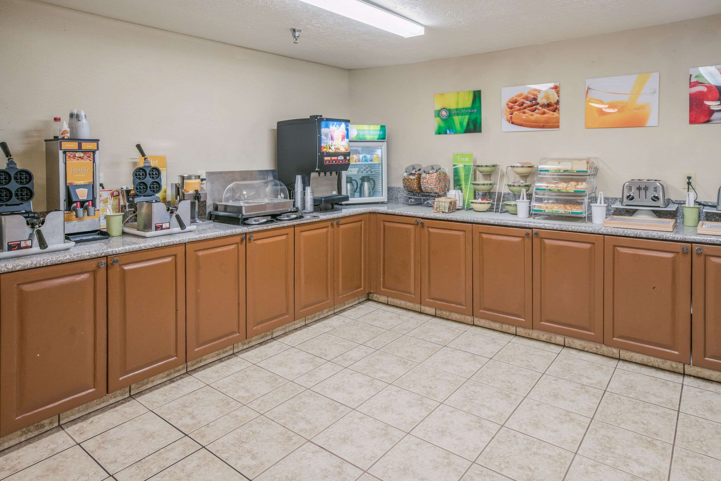 A kitchen with a waffle maker, coffee machine, and a refrigerator.