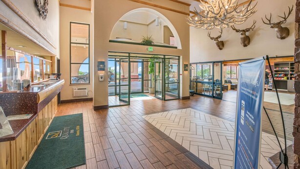 A lobby with a reception desk, a chandelier, and deer antlers on the wall. - Quality Inn Kanab National Park Area (Kanab)