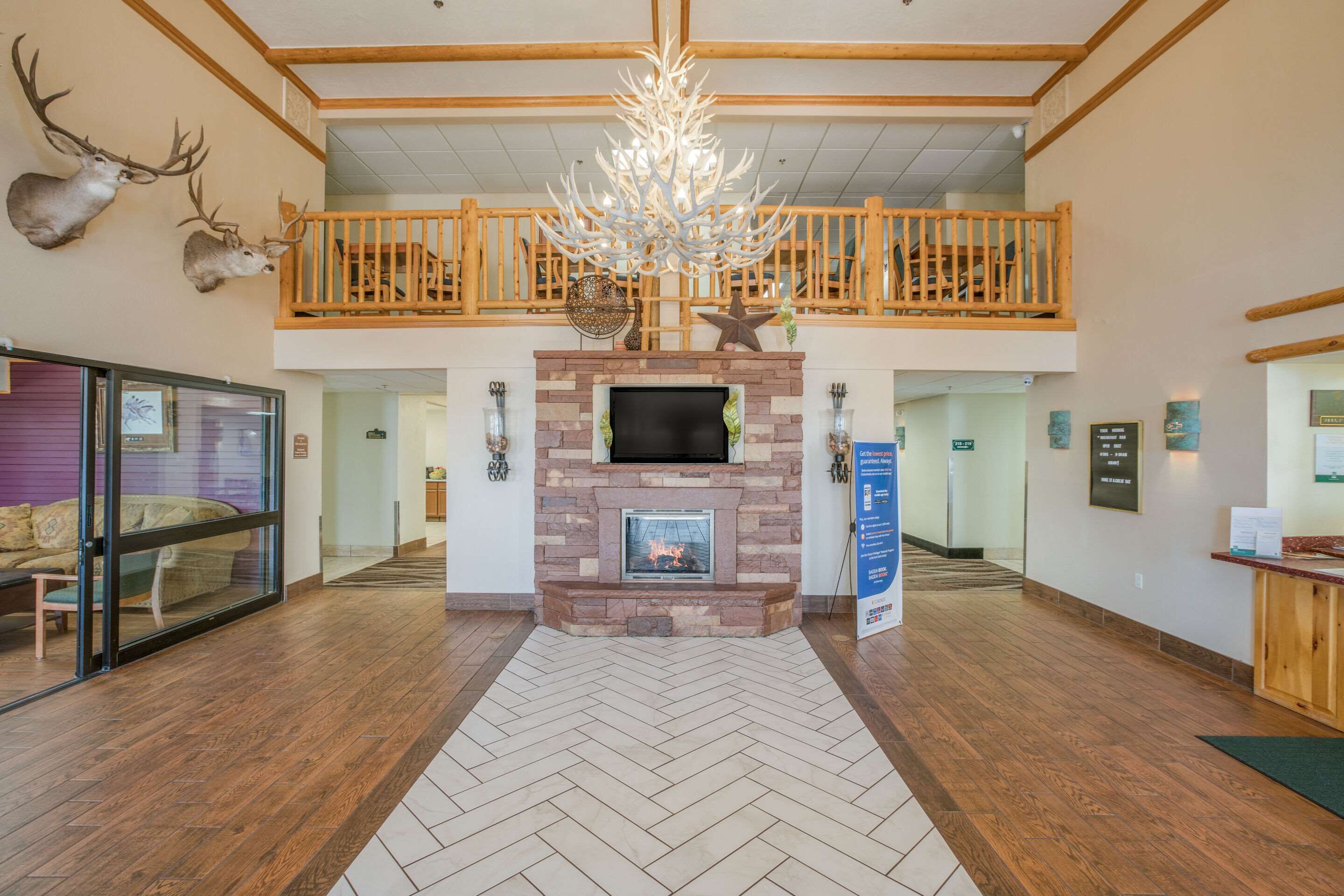 Un hall d’entrée spacieux doté d’une cheminée, d’un plancher en bois, d’un lustre et d’un balcon avec des balustrades en bois.