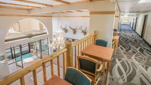 A hotel lobby with wooden beams, a patterned carpet, and a view of the outdoor area through an arched window. - Quality Inn Kanab National Park Area (Kanab)