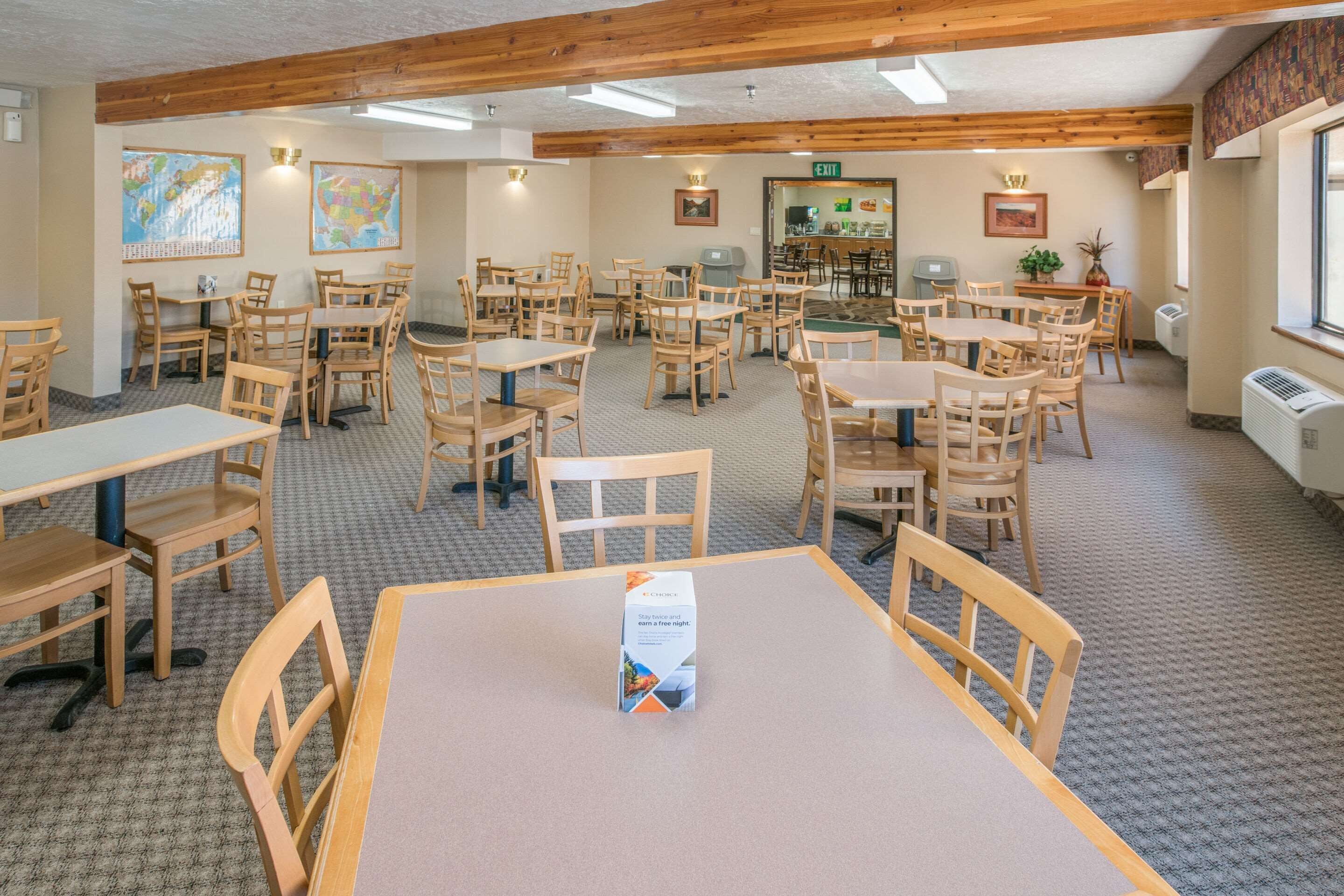 A dining area with wooden tables and chairs, a buffet setup, and a map on the wall.