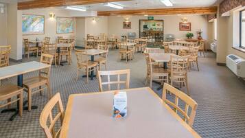 A dining area with wooden tables and chairs, a buffet setup, and a map on the wall.