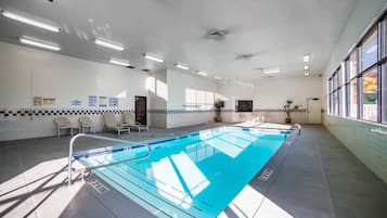 An indoor swimming pool with clear lane markings, a tiled floor, and a ceiling with recessed lighting.