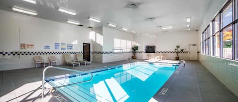 An indoor swimming pool with clear lane markings, a tiled floor, and a ceiling with recessed lighting.