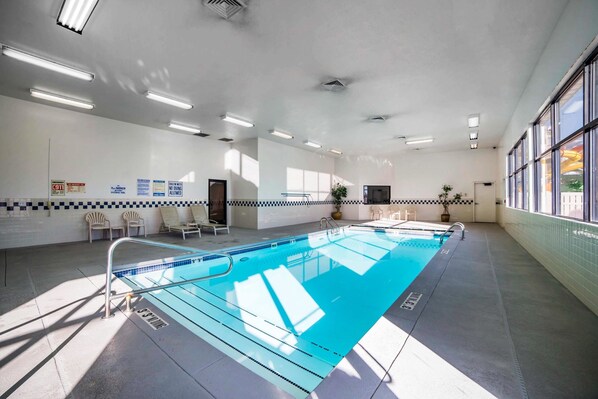 An indoor swimming pool with clear lane markings, a tiled floor, and a ceiling with recessed lighting.
