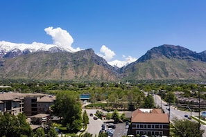 A residential area with a mountain range in the background, featuring a mix of single and multi-story buildings, a parking lot, and a clear sky. - Residence Inn by Marriott Provo North University (Provo)