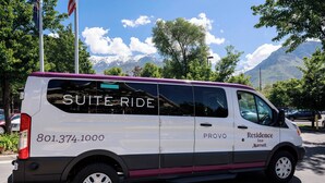 A white van with "Suite Ride" and "801.374.1000" on the side, parked on a street with a mountain and trees in the background. - Residence Inn by Marriott Provo North University (Provo)
