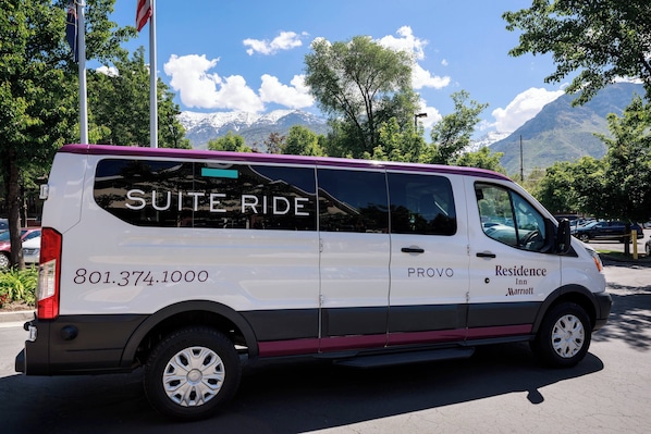 A white van with "Suite Ride" and "801.374.1000" on the side, parked on a street with a mountain and trees in the background. - Residence Inn by Marriott Provo North University (Provo)
