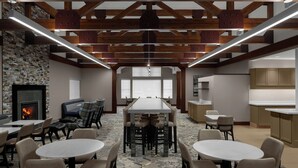 A spacious conference room with a long table, multiple chairs, a fireplace, and a kitchen area.