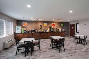 A modern kitchen area with a coffee station, dining tables, and chairs.