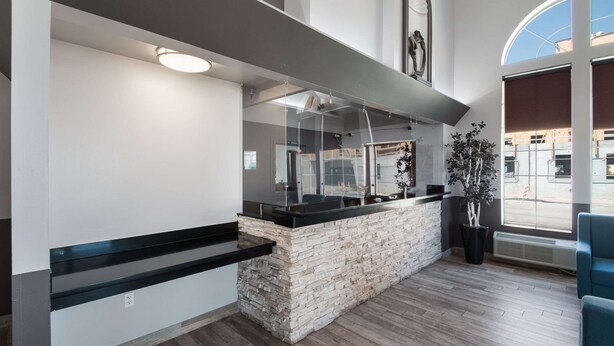 A reception area with a stone counter, a large window, and a potted plant. - Quality Inn Midvale - Salt Lake City South (Midvale)