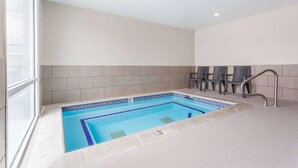 A swimming pool with a tiled edge, a tiled wall, and a window on one side. - Quality Inn Midvale - Salt Lake City South (Midvale)