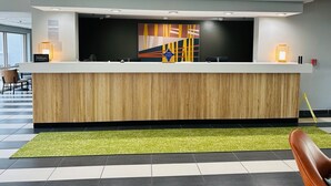 A hotel reception desk with a modern design, a check-in counter, and a large abstract painting above it. - Spark by Hilton Salem East Electric Road (Salem)