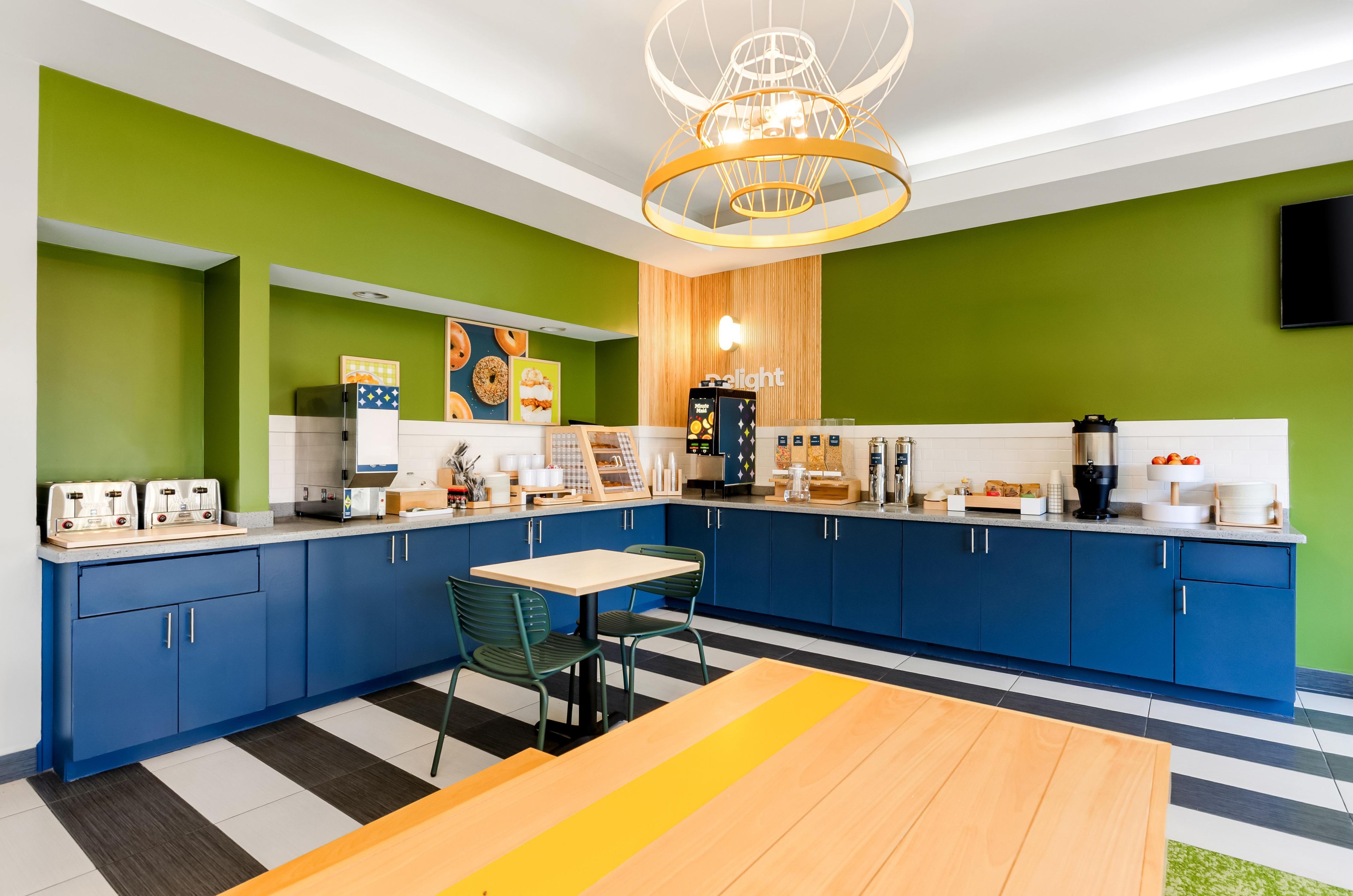 A modern kitchen with blue cabinets, a wooden table, and a unique chandelier.