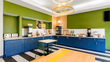 A modern kitchen with blue cabinets, a wooden table, and a unique chandelier.