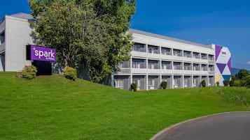 Un edificio moderno di un hotel con un cartello che riporta 'spark by Hilton' e un grande albero di fronte.
