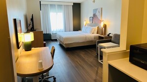 A hotel room with a bed, a desk, a chair, a television, and a window with curtains. - Spark by Hilton Salem East Electric Road (Salem)