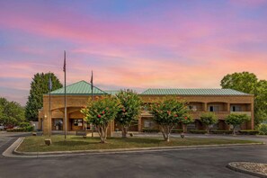 Hotel features a symmetrical design with a brick facade and lush greenery.