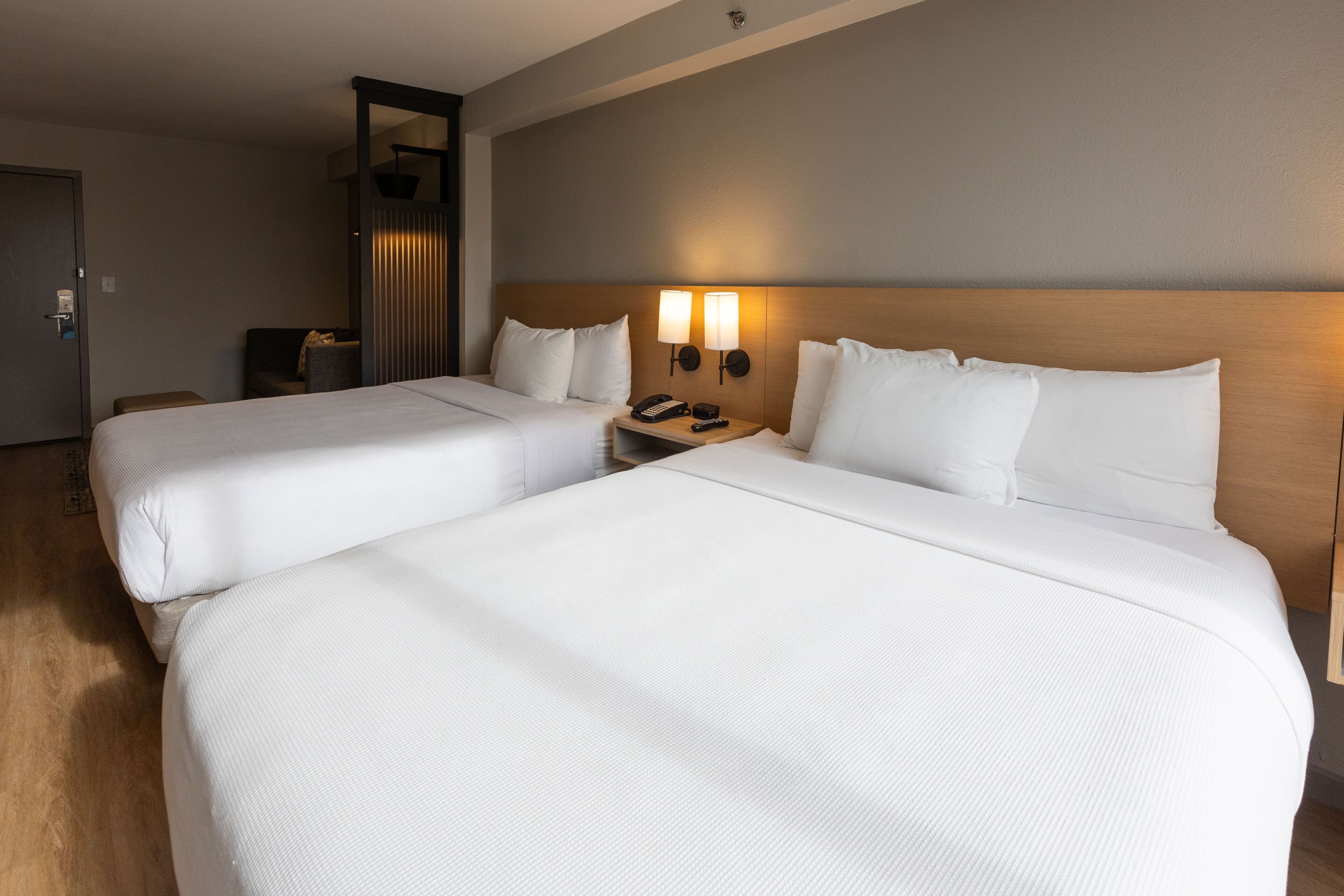 Ein Hotelzimmer mit zwei Betten, einem Nachttisch mit Telefon und einer Wandlampe.