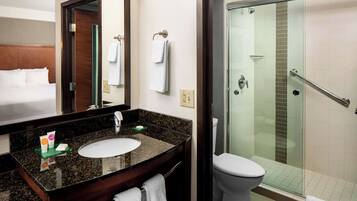 Un baño de hotel con lavamanos, espejo e inodoro.