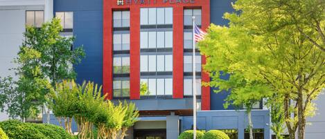 A modern Hyatt Place hotel with a blue facade, large windows, and an American flag.