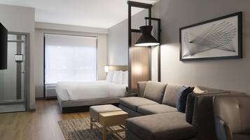 Et moderne hotelværelse med seng, sofa, skrivebord og et stort vindue.