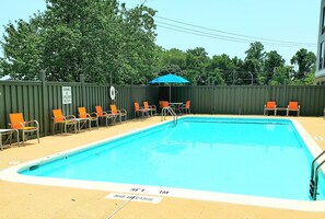 A swimming pool with a lifeguard sign, chairs, and a blue umbrella. - Holiday Inn Express Lorton by IHG (Lorton)