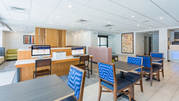 A modern hotel lobby with a reception desk, seating area, and artwork on the walls. - Holiday Inn Express Lorton by IHG (Lorton)