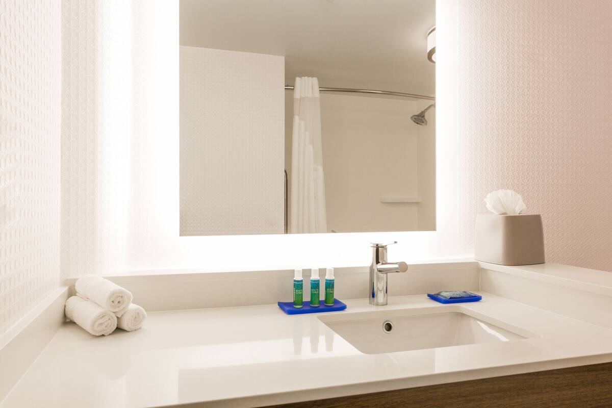 A bathroom with a white sink, a mirror, and a towel rack.