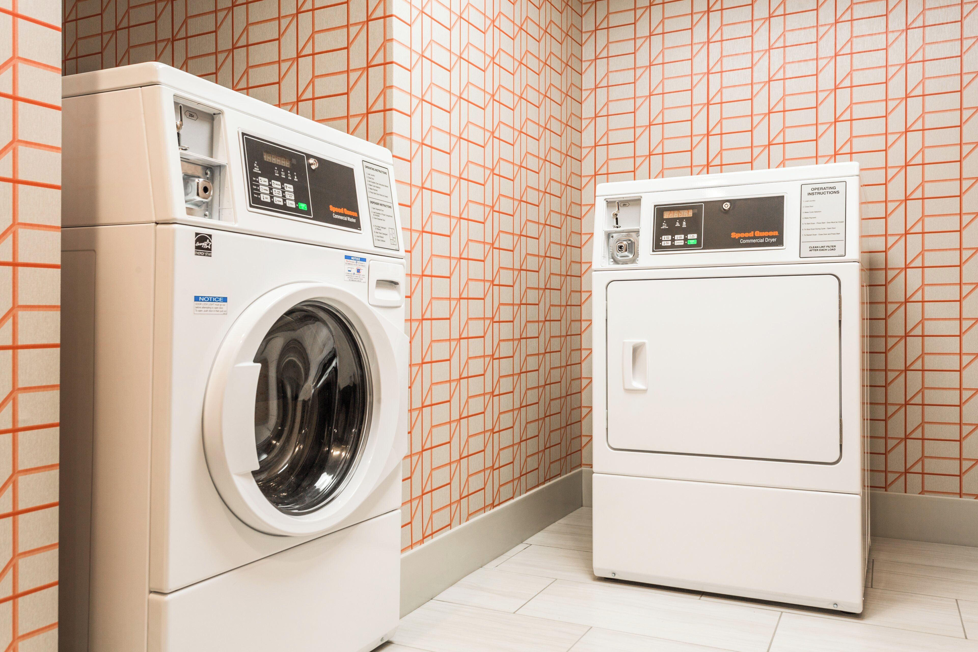 A laundry room with two front-loading washing machines and dryers.