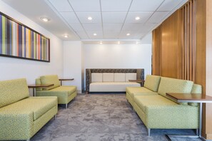 A hotel room with a sofa bed, two armchairs, a small table, and a wall-mounted TV. - Holiday Inn Express Lorton by IHG (Lorton)