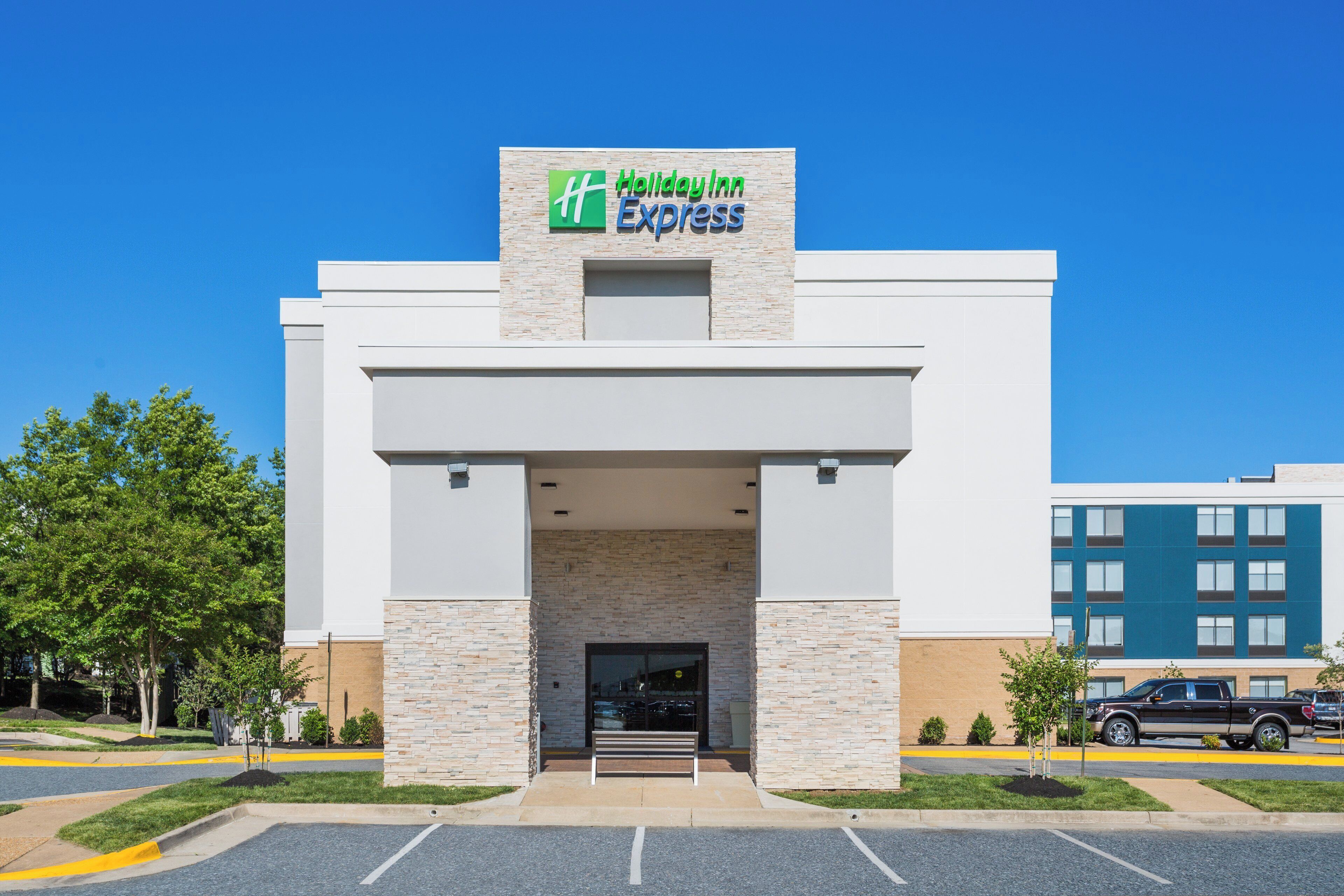 A Holiday Inn Express building with a stone facade, a flat roof, and a clear blue sky.
