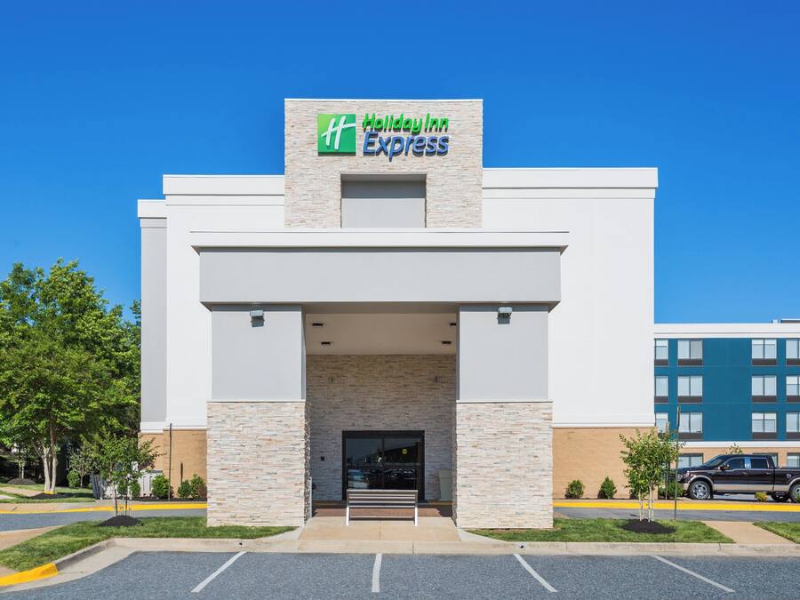 A Holiday Inn Express building with a stone facade, a flat roof, and a clear blue sky.