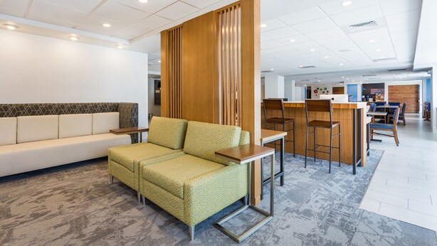 A modern hotel lobby with a sofa, a small table, and a bar area. - Holiday Inn Express Lorton by IHG (Lorton)