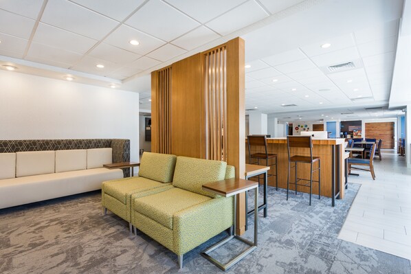 En moderne hotellobby med sofa, et lille bord og et barområde.