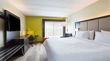 Une chambre d’hôtel avec un lit, un bureau, une chaise, une télévision et une fenêtre.