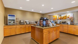A hotel kitchen with a central island, a refrigerator, and a coffee station. - Comfort Inn Quantico (Stafford)