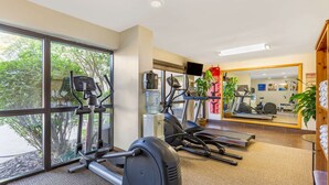 A gym with cardio equipment, large windows, and a view of trees. - Comfort Inn Quantico (Stafford)