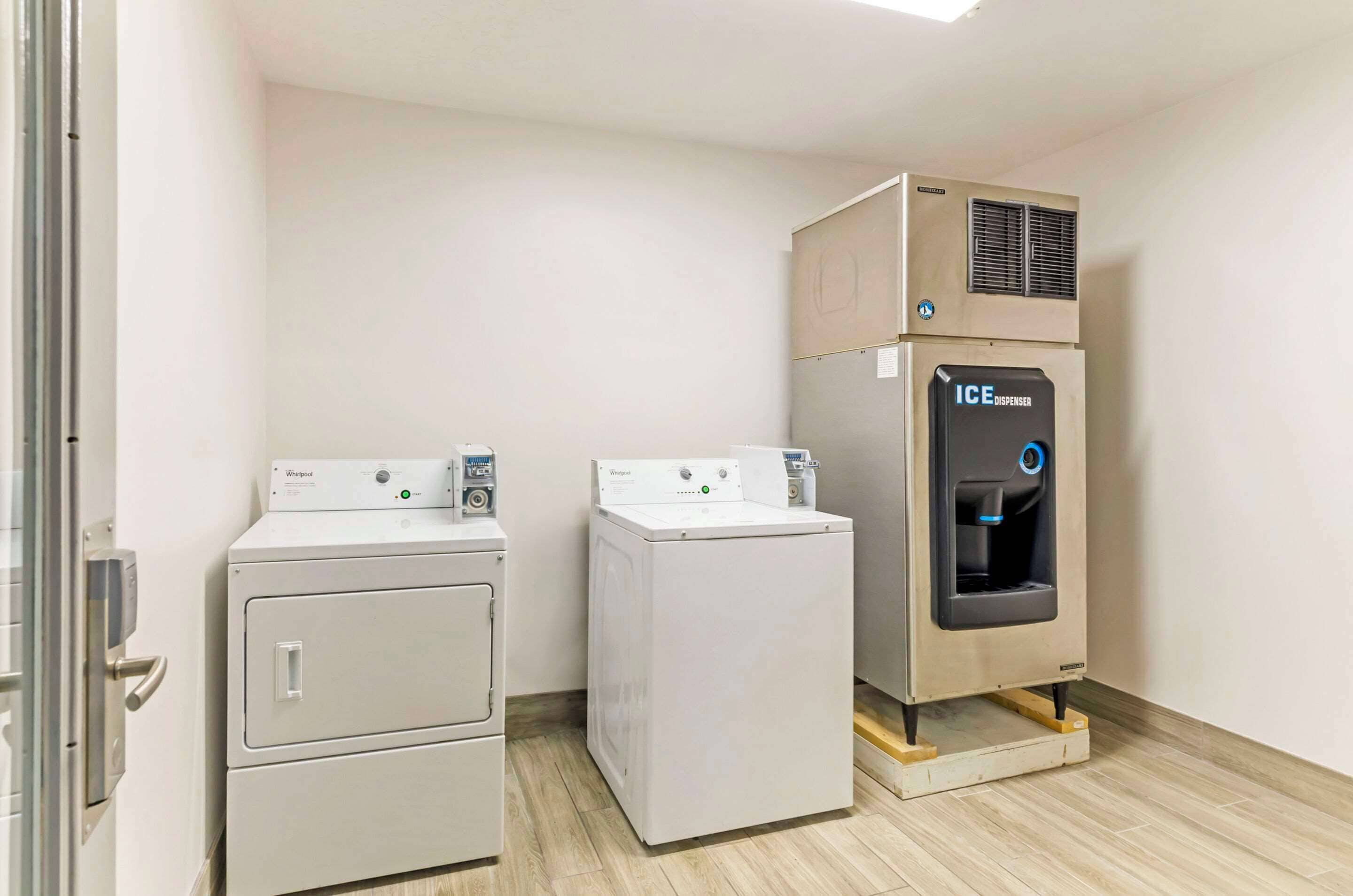Een wasruimte met twee voorladers en een in de muur gemonteerde ijsmachine.