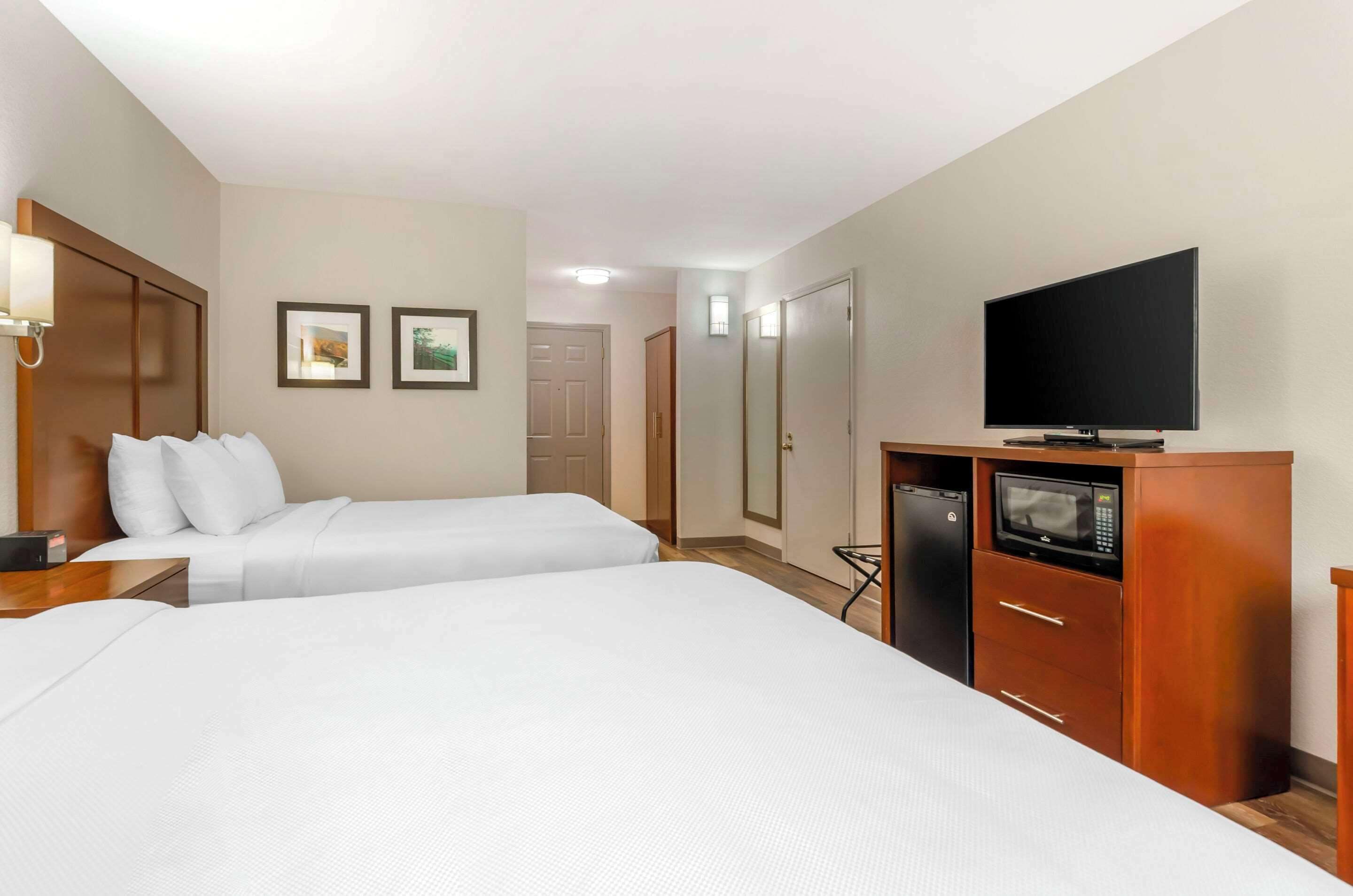 Ein Hotelzimmer mit zwei Betten, einem Fernseher, einer Mikrowelle und einem Kleiderschrank.