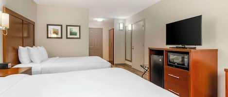Ein Hotelzimmer mit zwei Betten, einem Fernseher, einer Mikrowelle und einem Kleiderschrank.