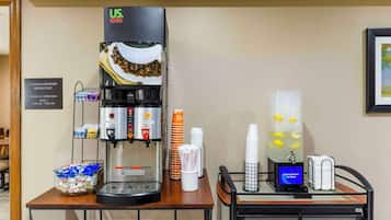 Een koffiehoek met een koffieapparaat van US Foods, een bordje met ‘complimentair ontbijt’ en een ijskoude waterdispenser met citroensmaak.